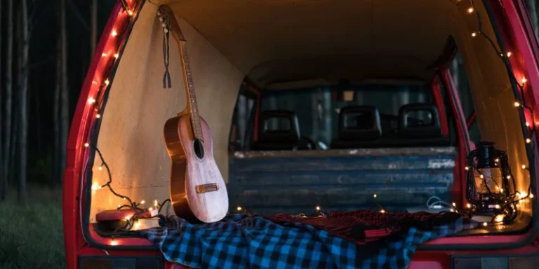 A serene camping scene with an acoustic guitar and lights in a car trunk