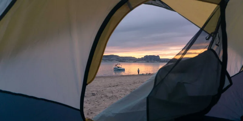 Tent view of a beach with a boat at sunset