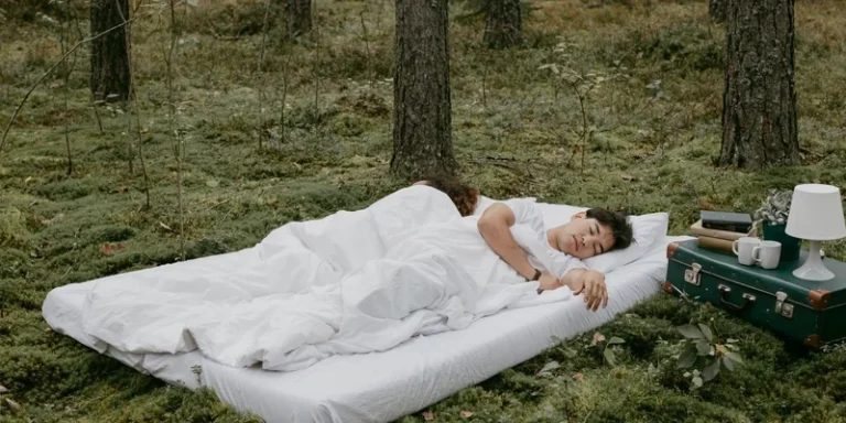 A couple peacefully sleeping on a mattress in a forest setting