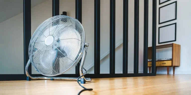 A sleek electric fan placed on a wooden floor in a modern indoor setting