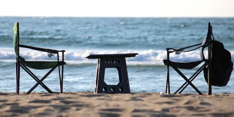Scenic beach with camping chairs and table facing ocean waves