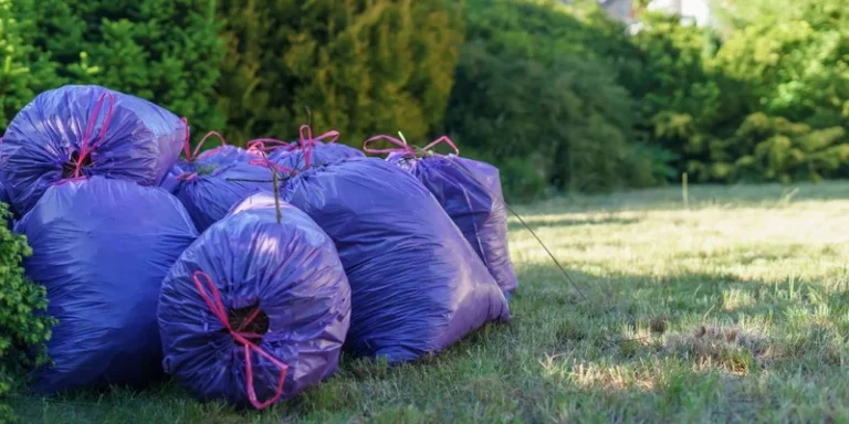 Vibrant purple trash bags stacked in a sunlit garden setting
