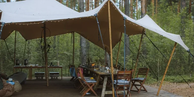 Cozy outdoor campsite with a large tent and wooden tables set in a forest environment
