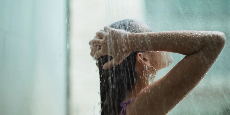 Young woman with long hair enjoying a refreshing outdoor shower