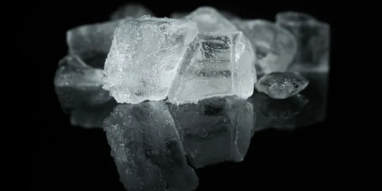 A detailed close-up of ice cubes reflecting on a dark surface