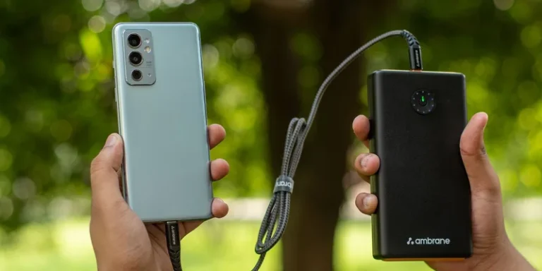 Close-up of hands holding a smartphone connected to a power bank outdoors