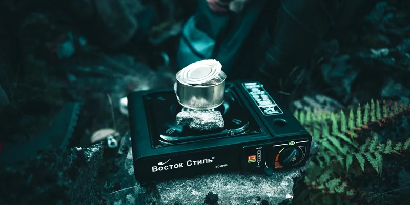 A portable gas stove heating a canned meal outdoors