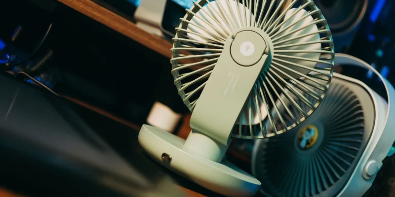 Photo of a desk setup featuring a modern compact fan, emphasizing technology and comfort