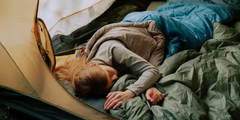 A serene scene of a woman sleeping comfortably in a tent during a camping trip, surrounded by nature