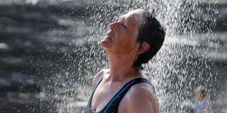 Woman enjoying a refreshing outdoor shower under a sunny sky, embracing nature