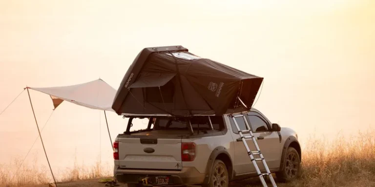 Pickup truck with rooftop tent in scenic outdoor camping setup at sunset